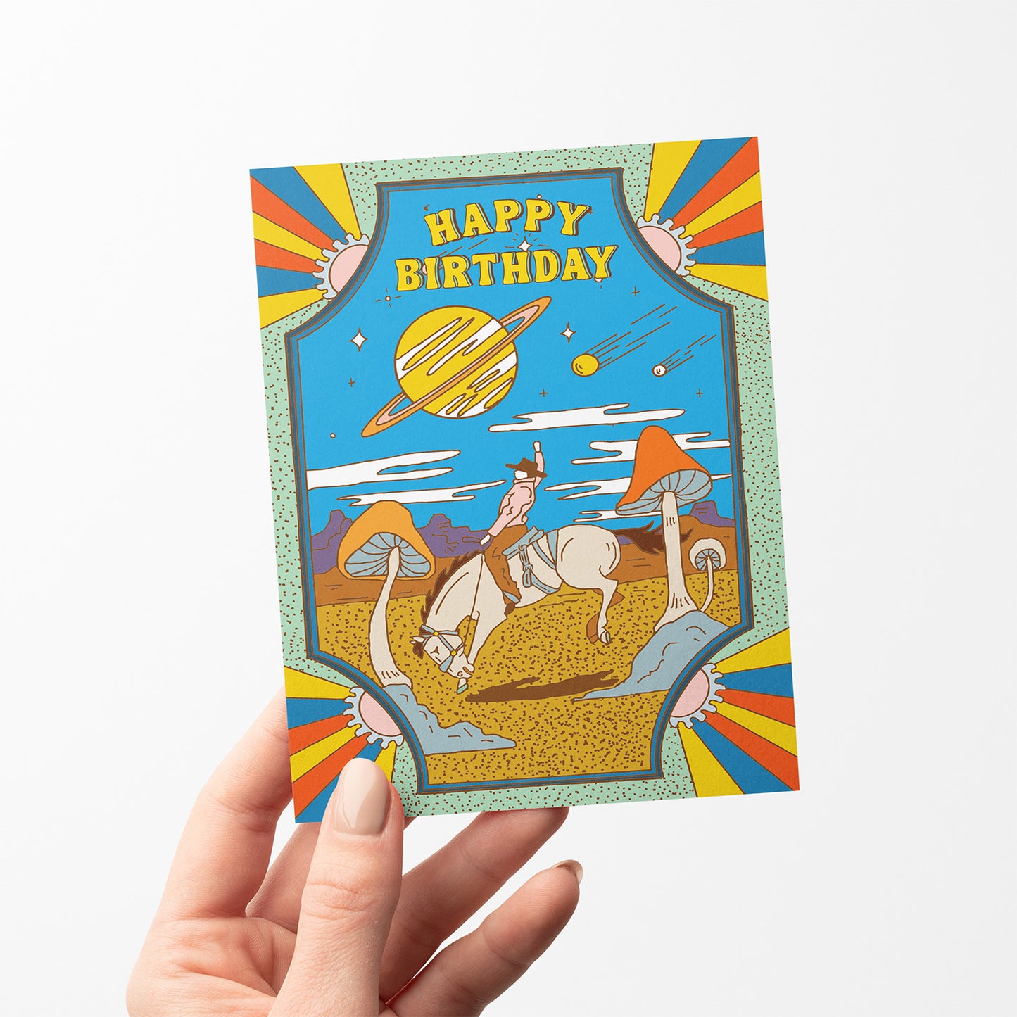 Psychedelic birthday card with cowboy on horseback in desert, giant mushrooms, ringed planet, and shooting stars.