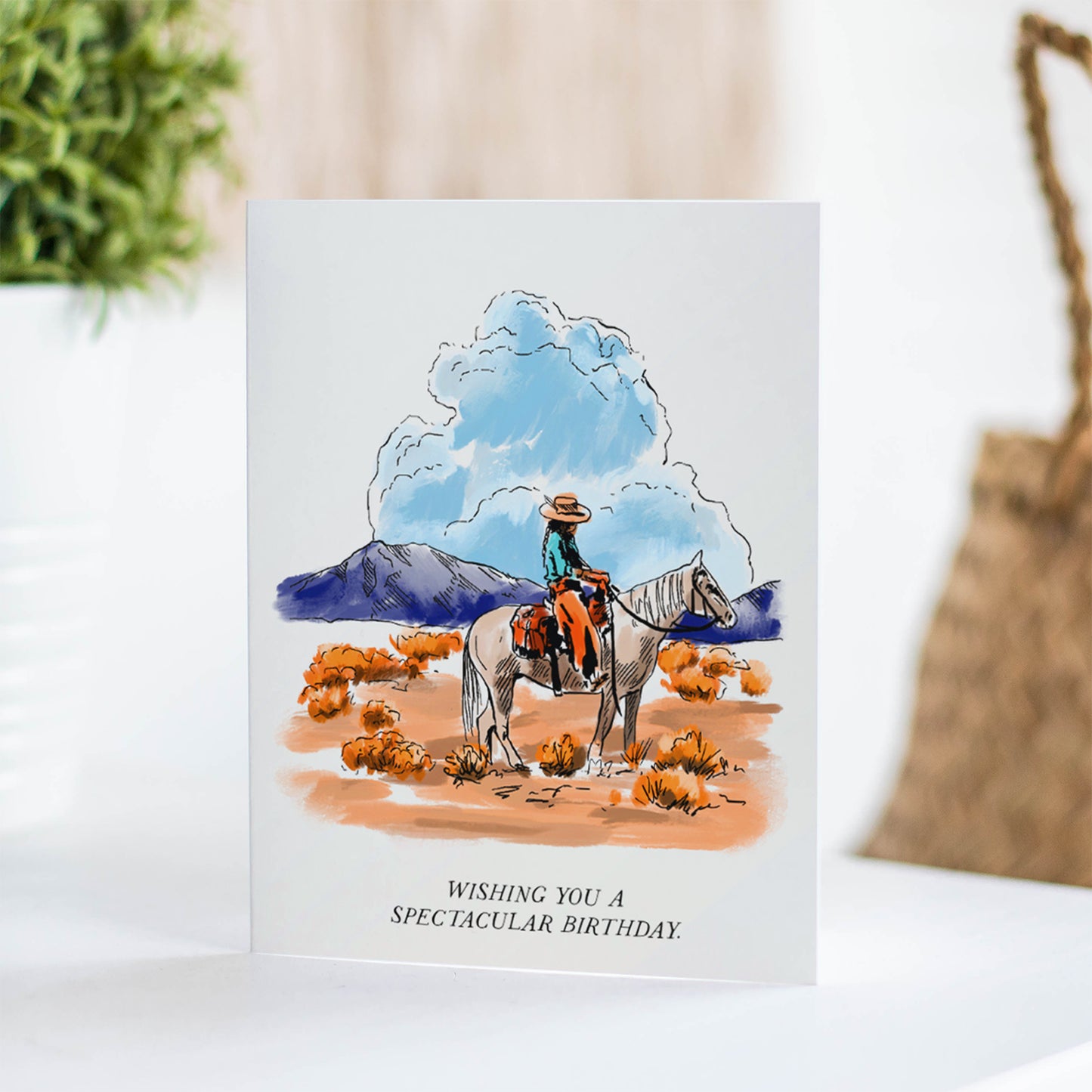 Rustic birthday card depicting expansive high plains with rolling hills and wide-open skies, and a cowboy on his horse, capturing the essence of the great outdoors.