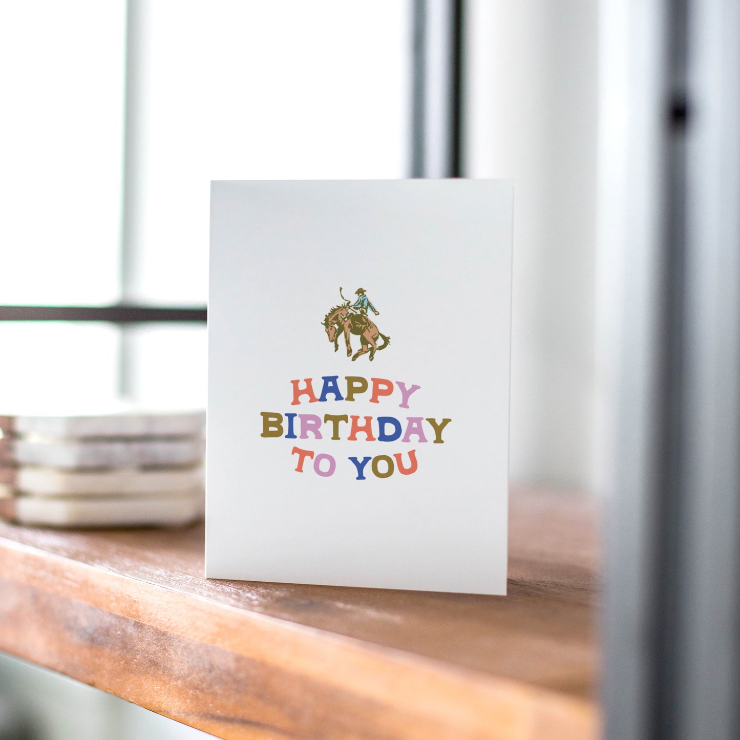 Birthday card with a cowboy riding a horse and colorful 'Happy Birthday To You' text