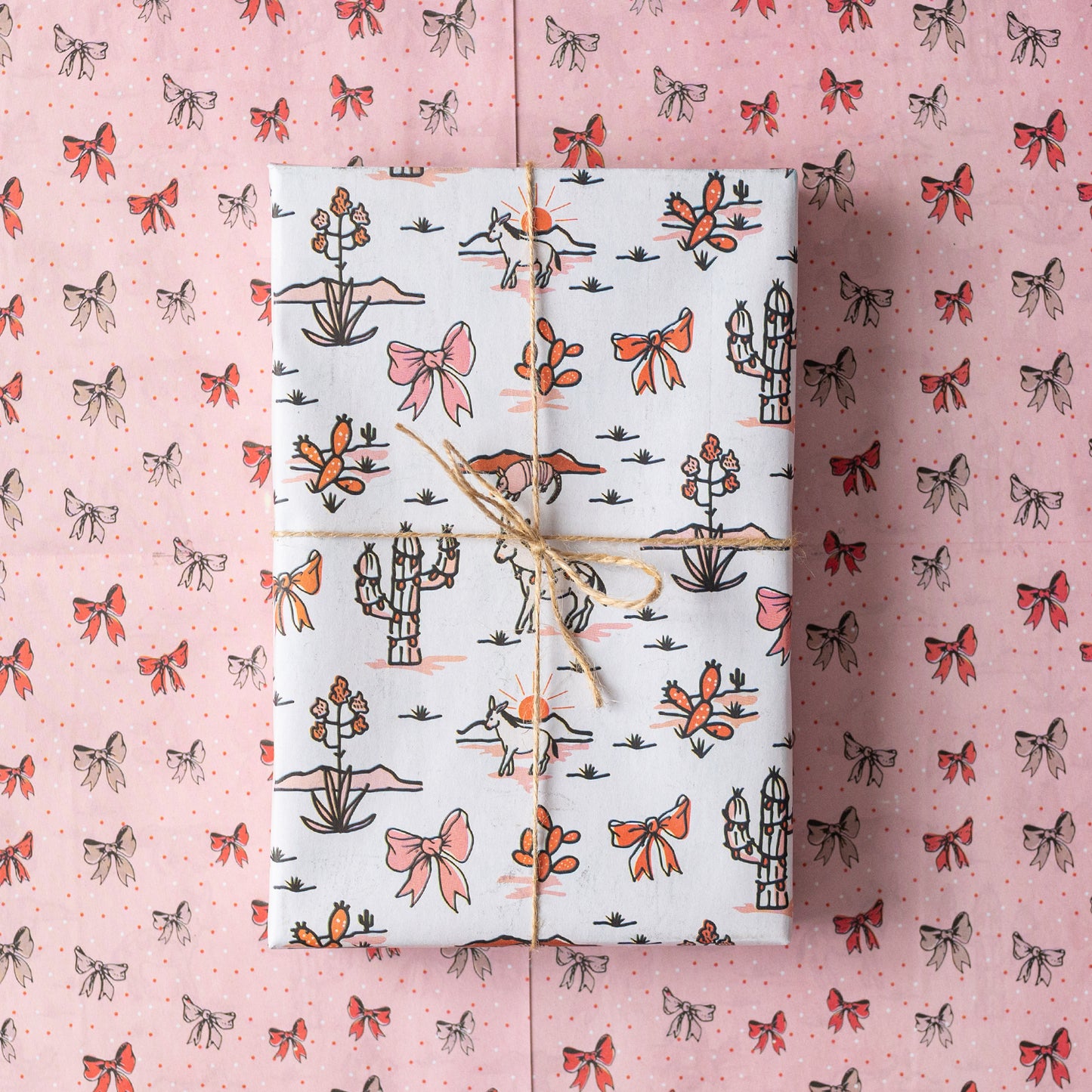 Double-sided sustainable gift wrap with cheerful desert themed holiday patterns on one side and holiday bows on the reverse, perfect for eco-friendly celebrations. 100% recyclable and compostable.