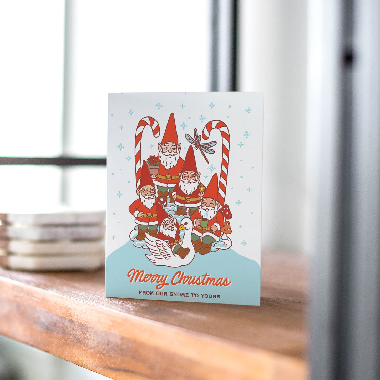 Christmas card with garden gnomes, candy canes, snowy background, and the text “Merry Christmas from our gnome to yours.”