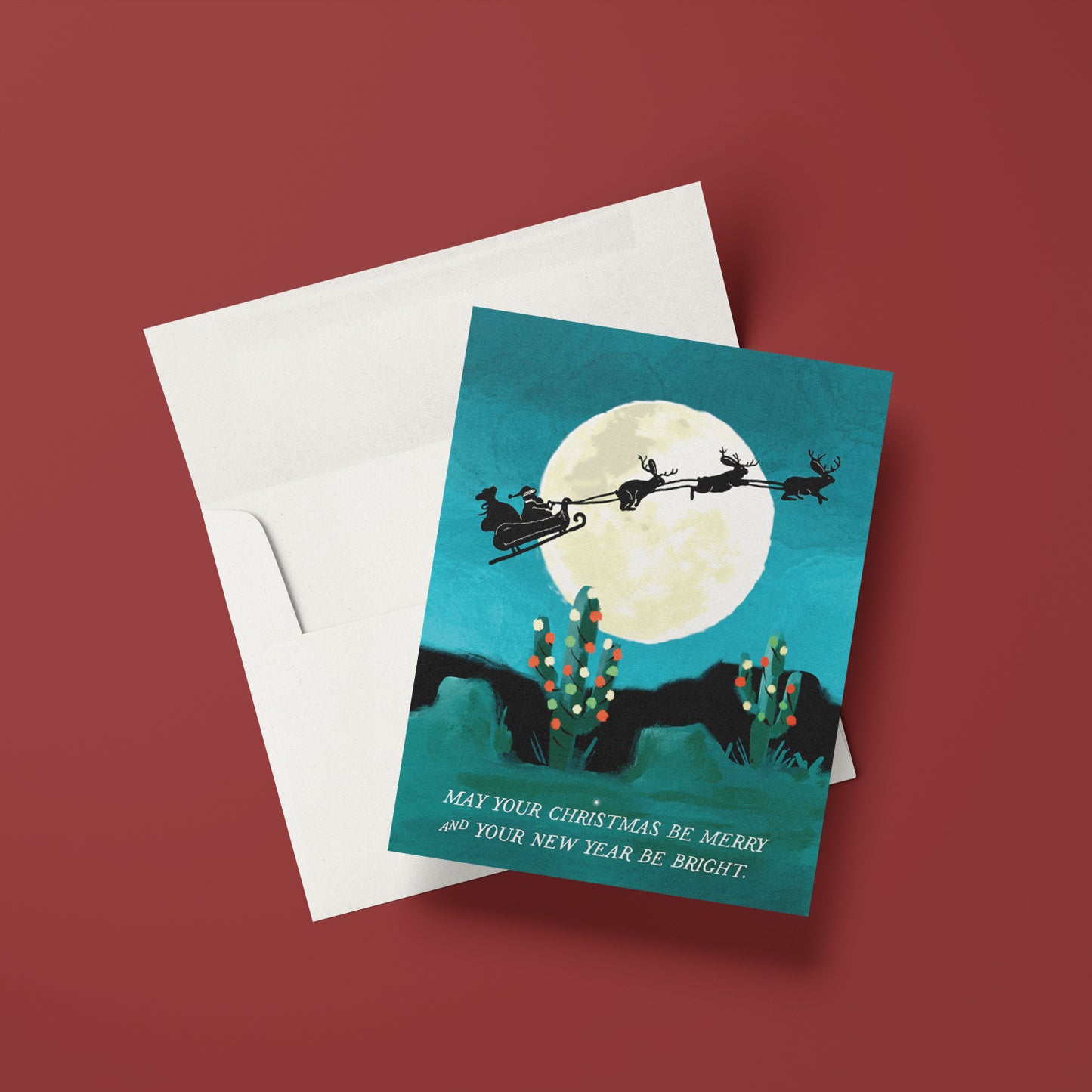 Jackelope Santa holiday card featuring jackelopes pulling Santa's slay across a full moon over a desert landscape, ideal for a unique holiday greeting, blank inside.