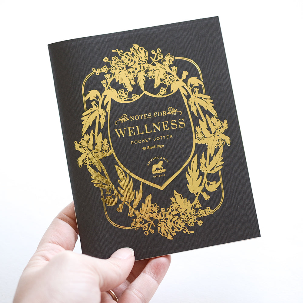 Black softcover staple-bound notebook featuring a botanical design. Blank interior pages.