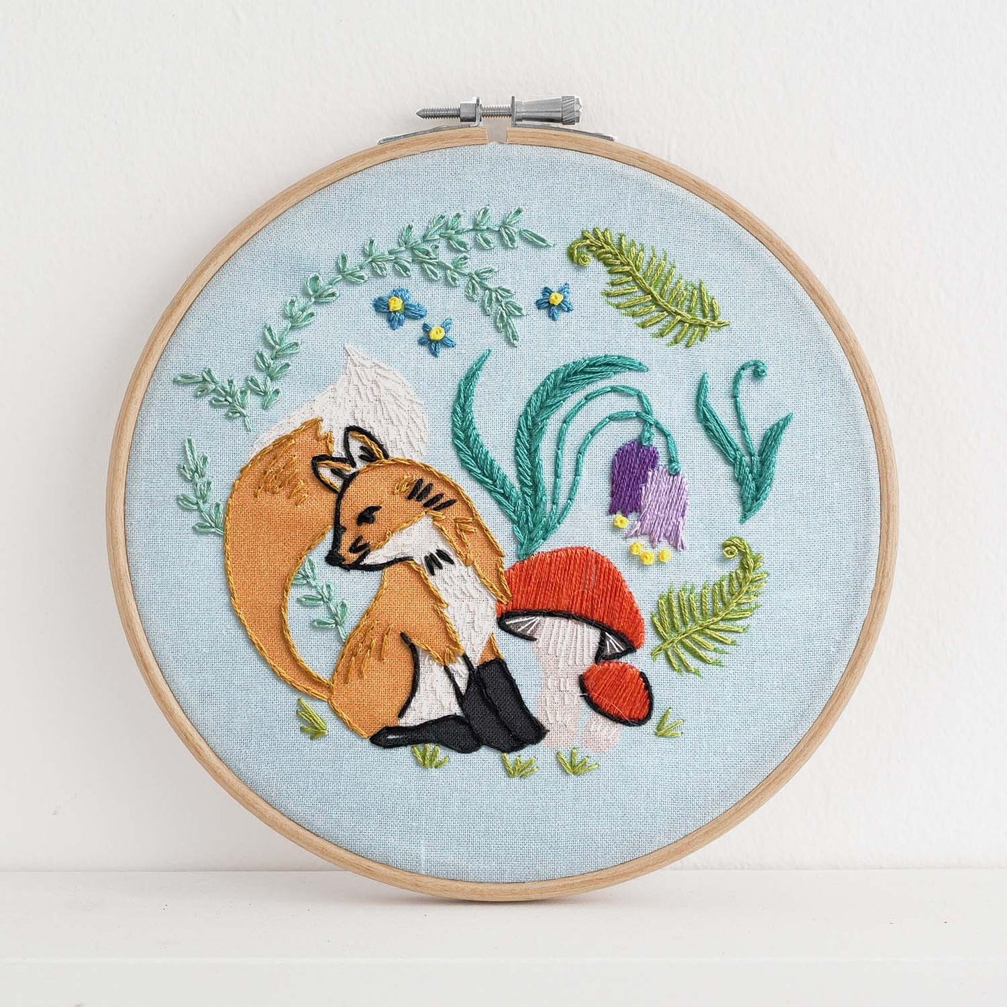 Embroidery kit with fabric, wooden hoop, thread, needle, and instructions for beginners, featuring cute fox surrounded by different flora and fauna 