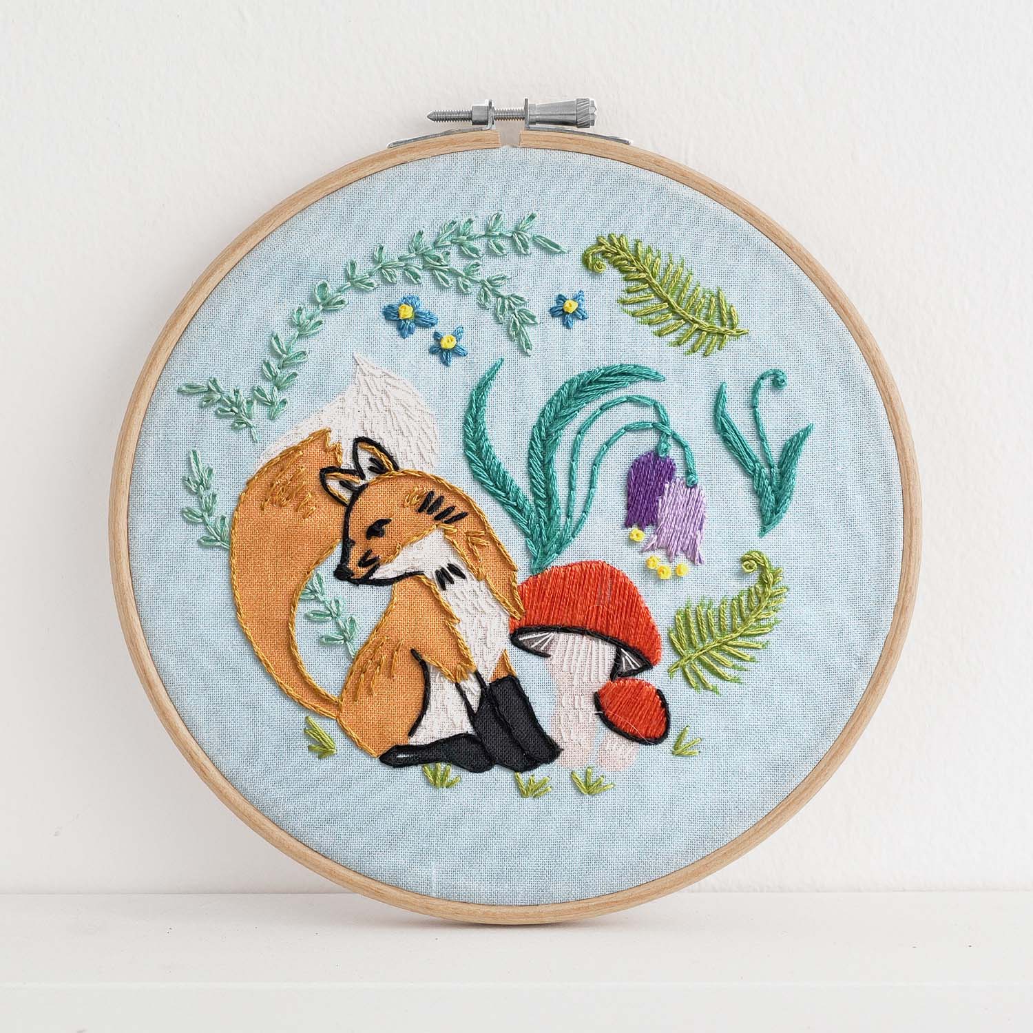 Embroidery kit with fabric, wooden hoop, thread, needle, and instructions for beginners, featuring cute fox surrounded by different flora and fauna 