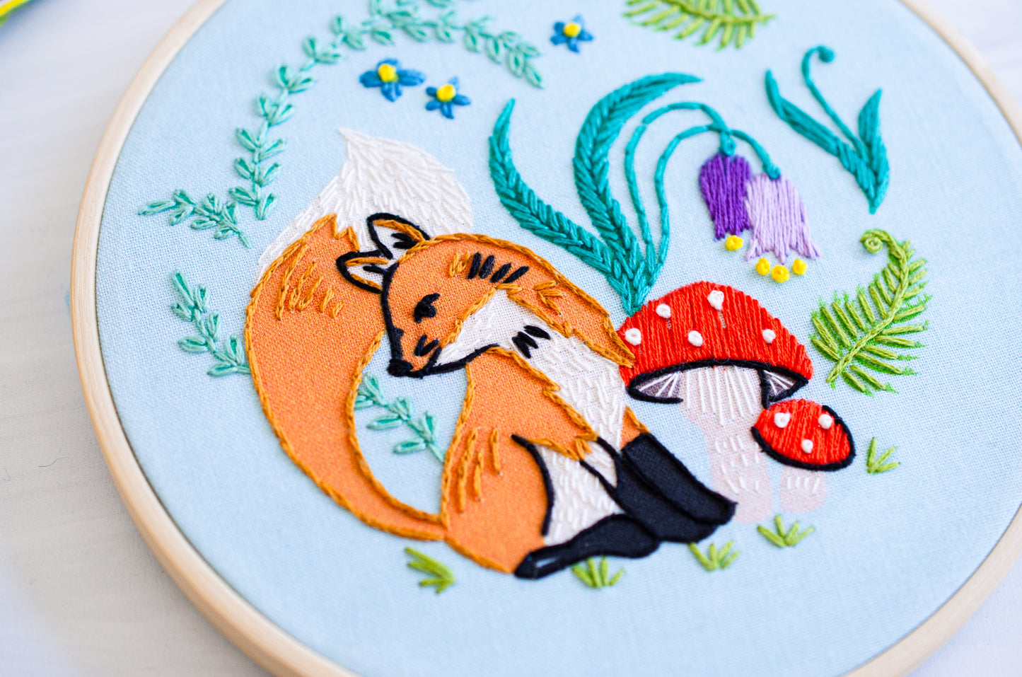 Embroidery kit with fabric, wooden hoop, thread, needle, and instructions for beginners, featuring cute fox surrounded by different flora and fauna 