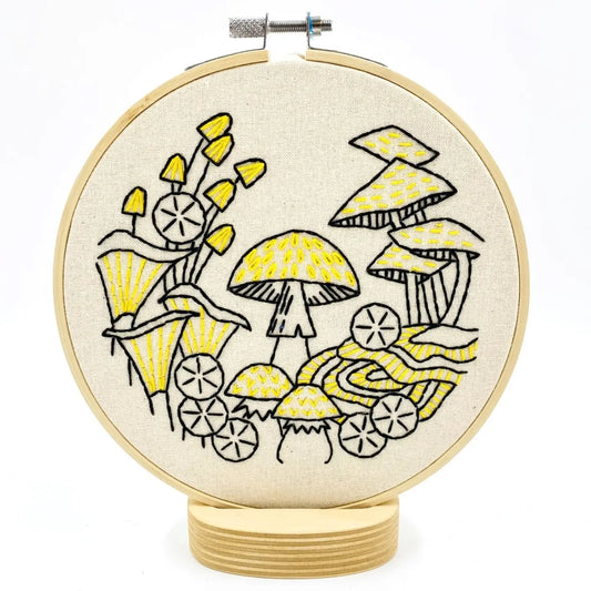 Embroidery kit with fabric, wooden hoop, thread, needle, and instructions for beginners, featuring a mushroom design.