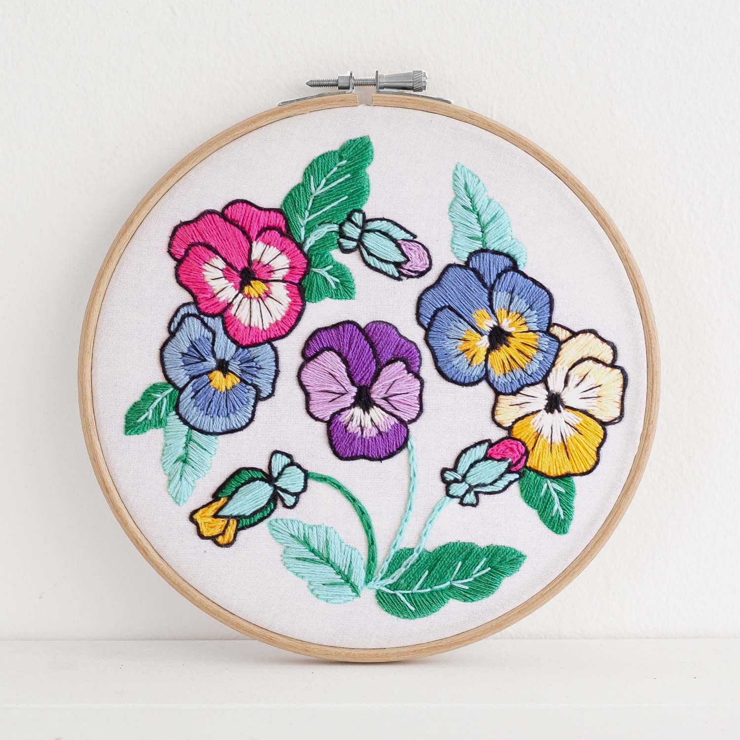 Embroidery kit with fabric, wooden hoop, thread, needle, and instructions for beginners, featuring brightly colored pansies