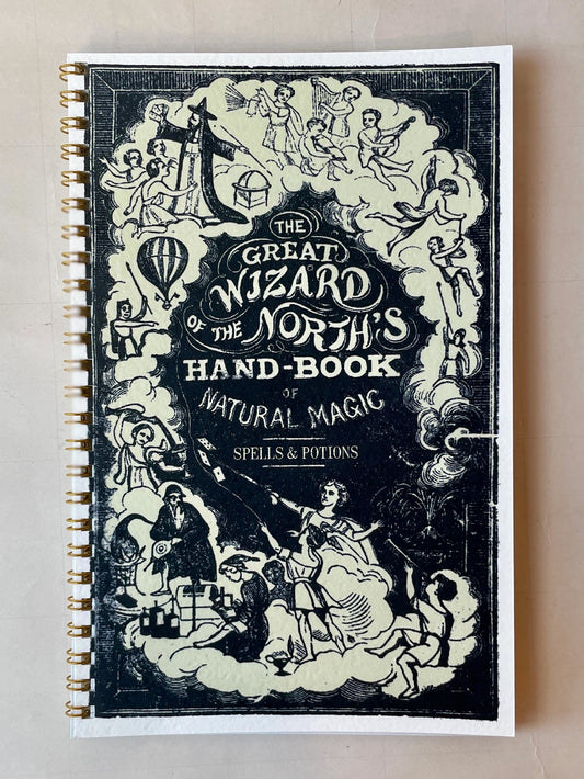 black and white softcover spiral-bound notebook featuring a fantastical design. lined interior pages. 