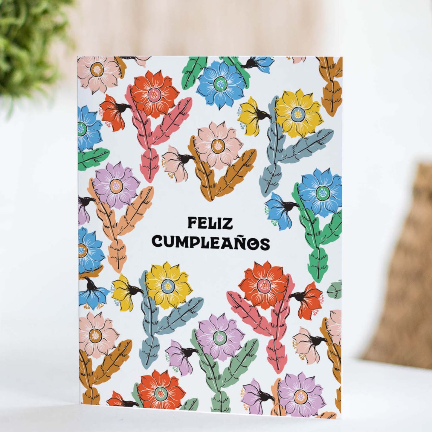 Elegant birthday card with blooming orchid cacti and vibrant colors, featuring the phrase 'Feliz Cumpleaños' for a festive celebration.