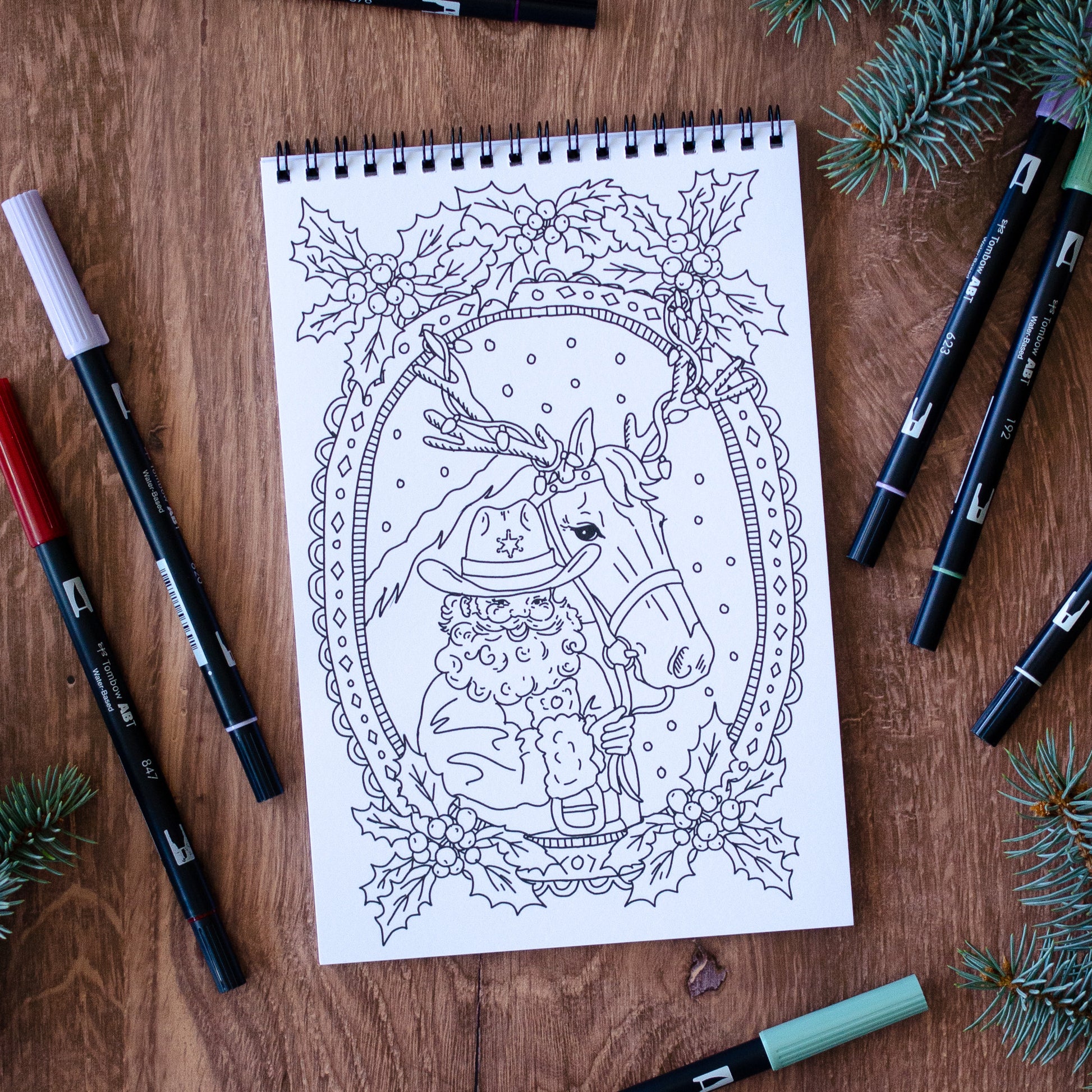 Coloring book page with a horse illustration surrounded by decorative elements on a wooden surface with markers.