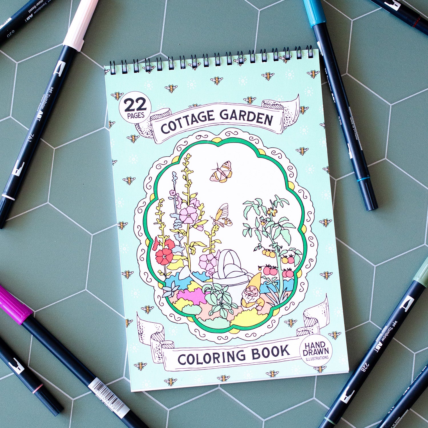 Cottage Garden Coloring Book with 22 pages of hand-drawn illustrations featuring flowers, bees, butterflies, and a whimsical garden gnome. Spiral-bound adult coloring book with intricate botanical designs, perfect for relaxation and creativity.