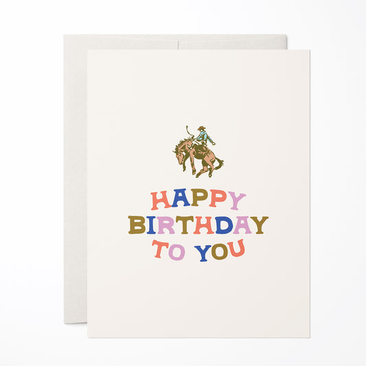 Birthday card with a cowboy riding a horse and colorful 'Happy Birthday To You' text