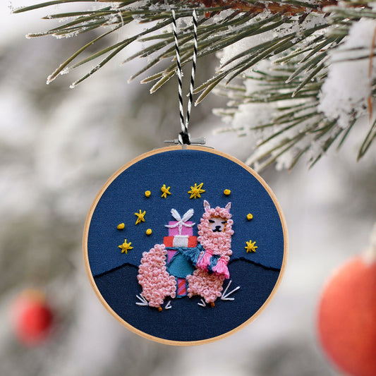 Embroidery Ornament kit with fabric, wooden hoop, thread, needle, and instructions for beginners, featuring an adorable alpaca carrying presents