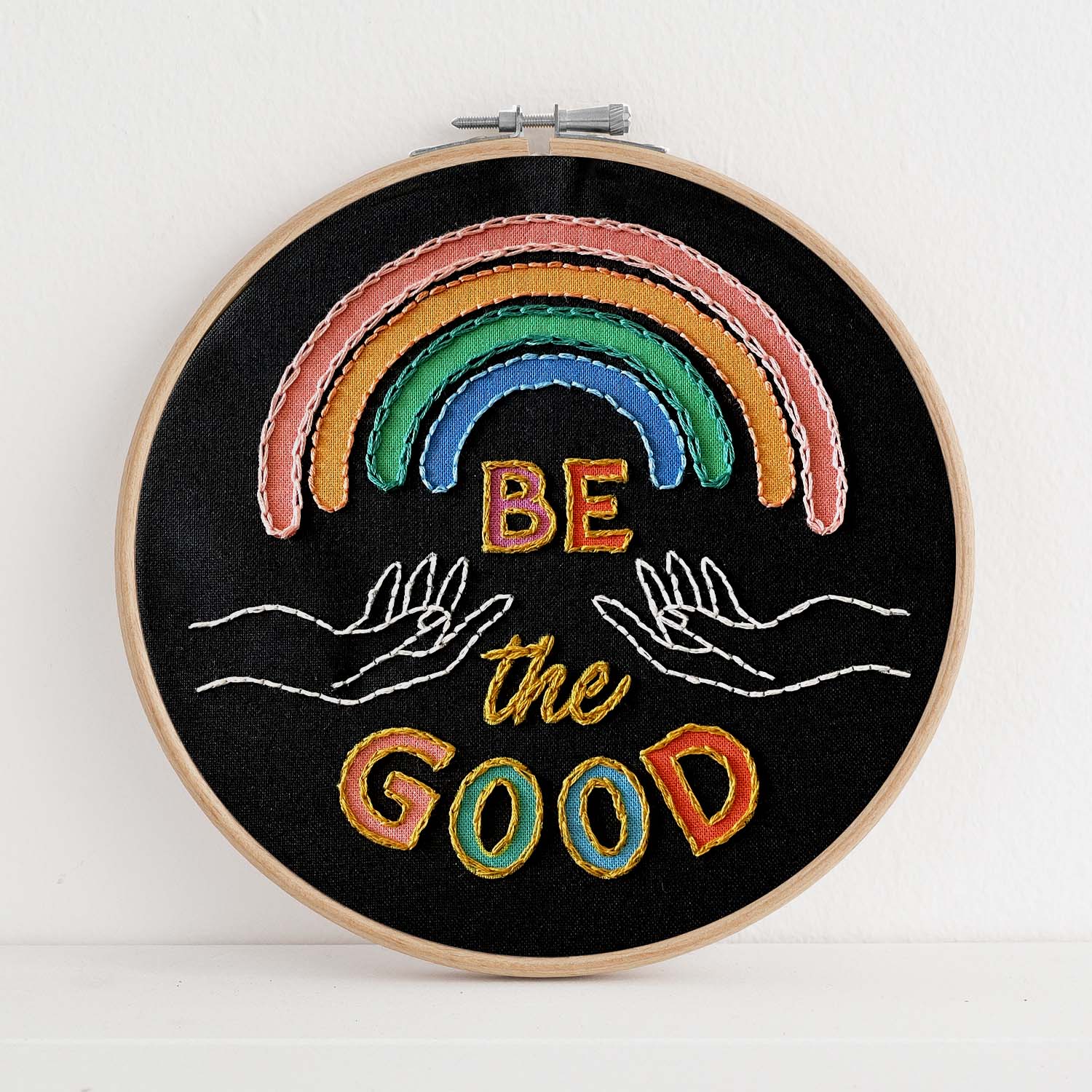 Embroidery kit with fabric, wooden hoop, thread, needle, and instructions for beginners, featuring a rainbow and the saying "be the good"
