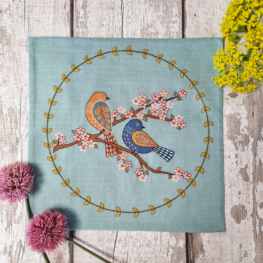 Embroidery kit with fabric, wooden hoop, thread, needle, and instructions for beginners, featuring a bird and blossom design.