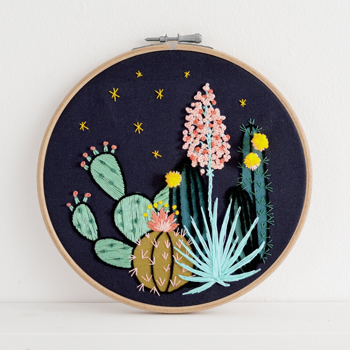 Embroidery kit with fabric, wooden hoop, thread, needle, and instructions for beginners, featuring a night time desert scene 
