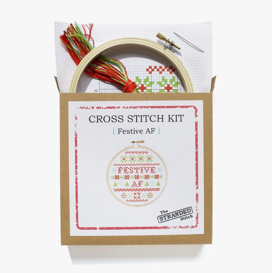 Cross stitch kit with fabric, wooden hoop, thread, needle, and instructions for beginners, featuring a festive saying design.