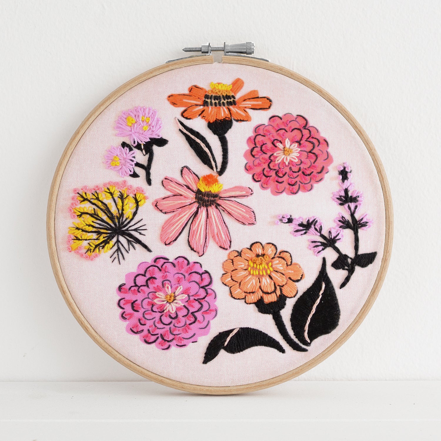 Embroidery kit with fabric, wooden hoop, thread, needle, and instructions for beginners, featuring brightly colored zinnia flowers