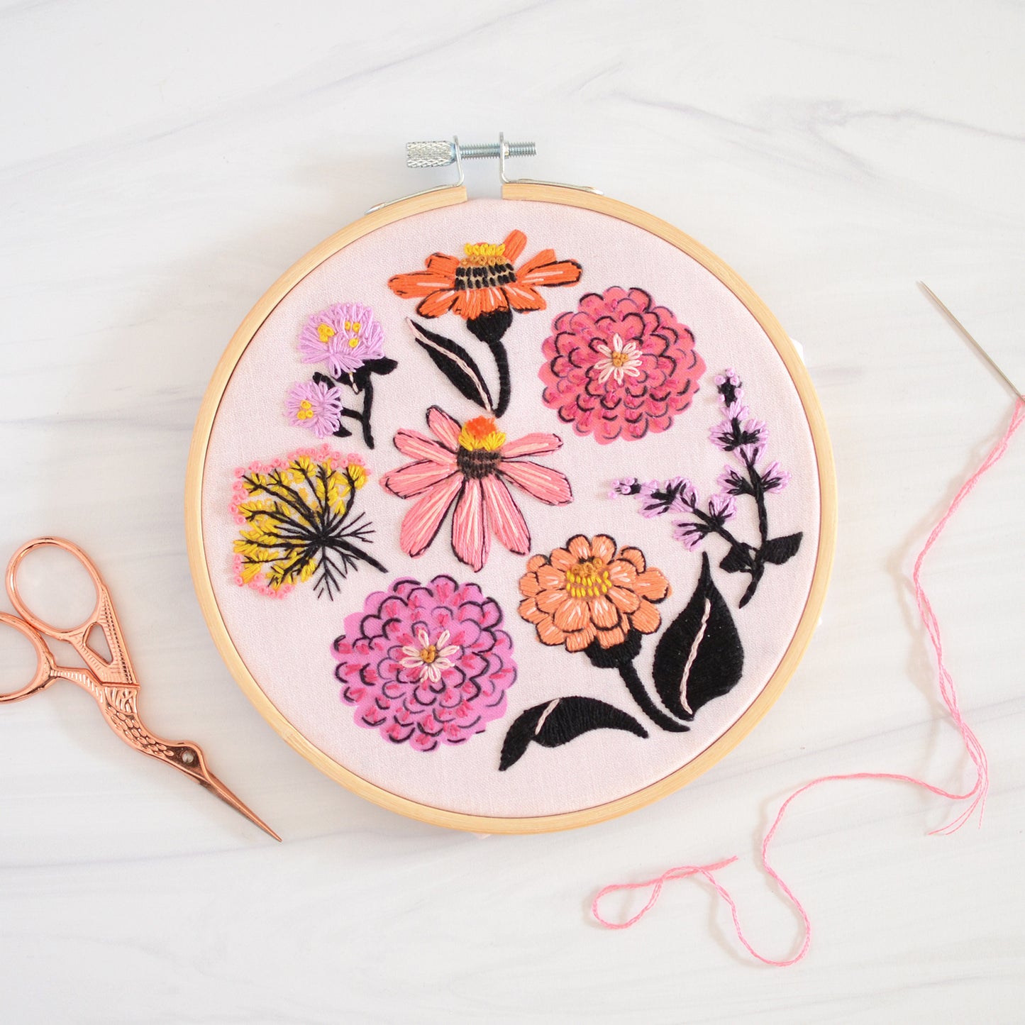 Embroidery kit with fabric, wooden hoop, thread, needle, and instructions for beginners, featuring brightly colored zinnia flowers