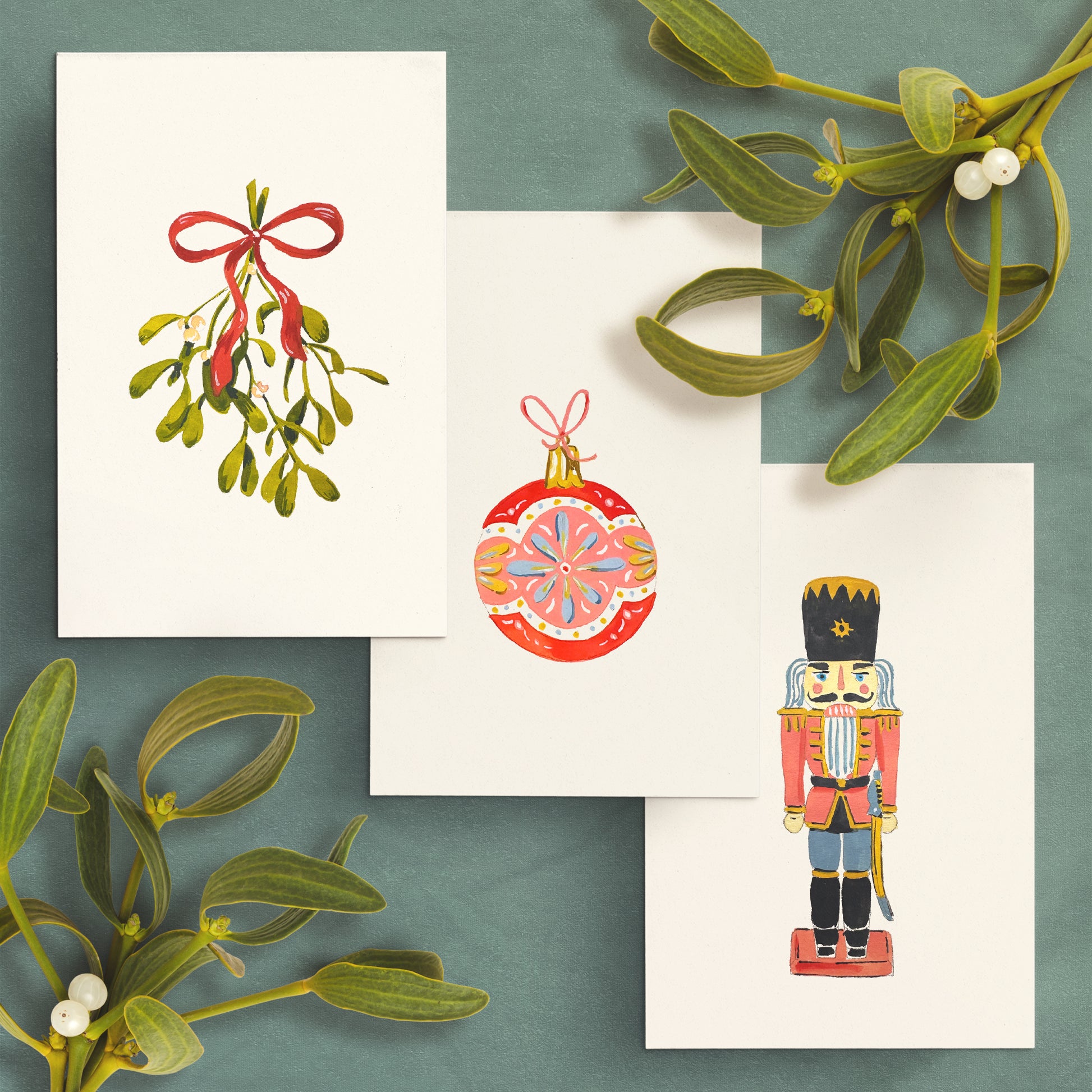 Set of Christmas-themed cards with mistletoe, nutcracker, and ornament designs on a green background.