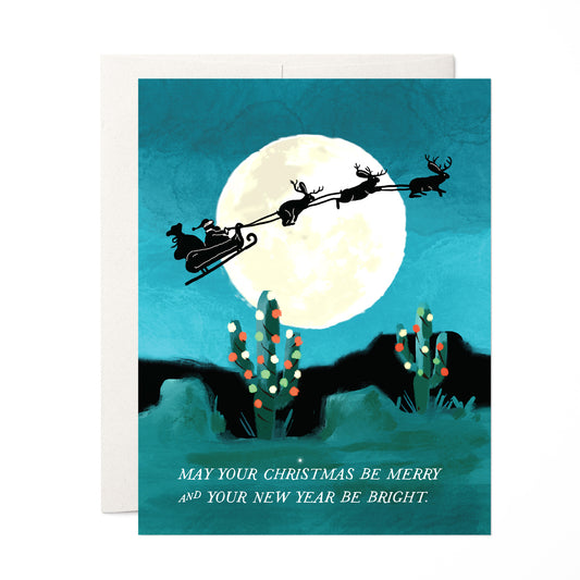 Jackelope Santa holiday card featuring jackelopes pulling Santa's slay across a full moon over a desert landscape, ideal for a unique holiday greeting, blank inside.