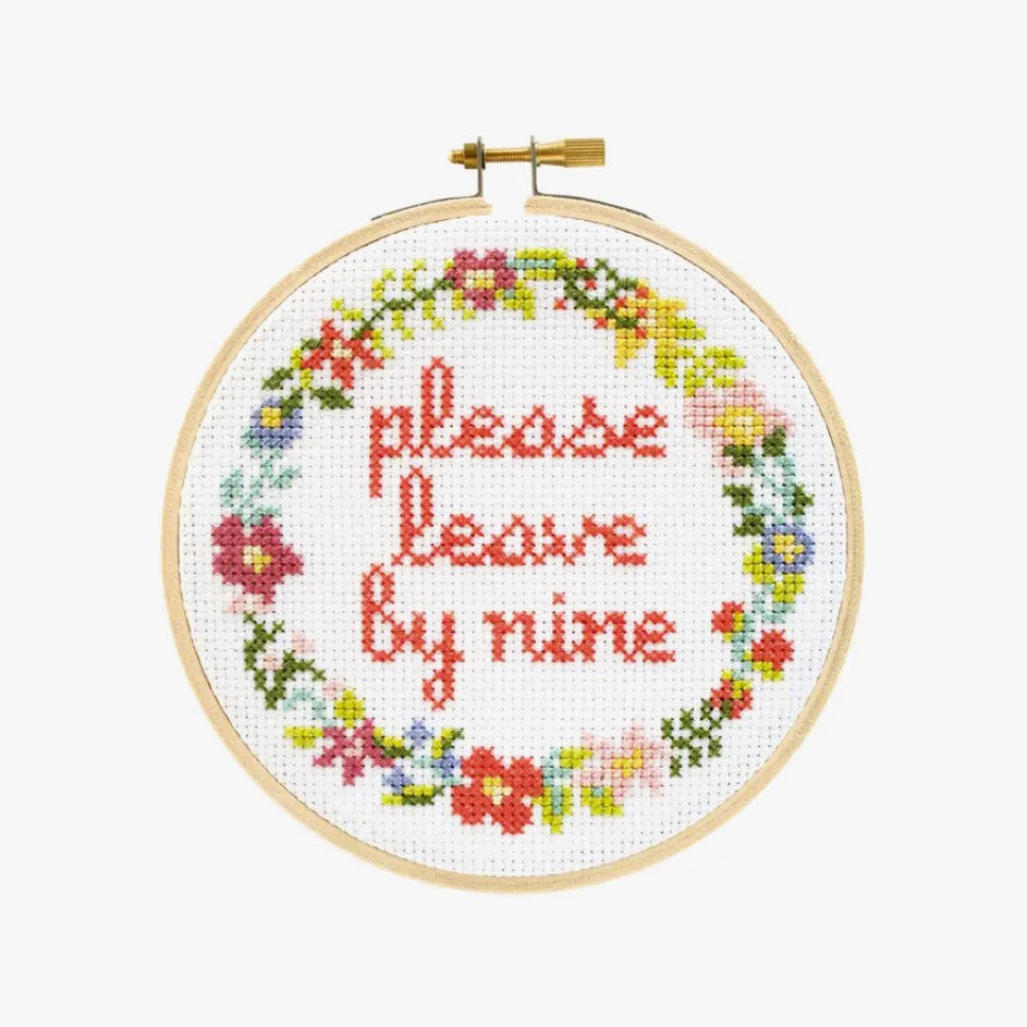 Cross stitch kit with fabric, wooden hoop, thread, needle, and instructions for beginners, saying "please leave by nine".