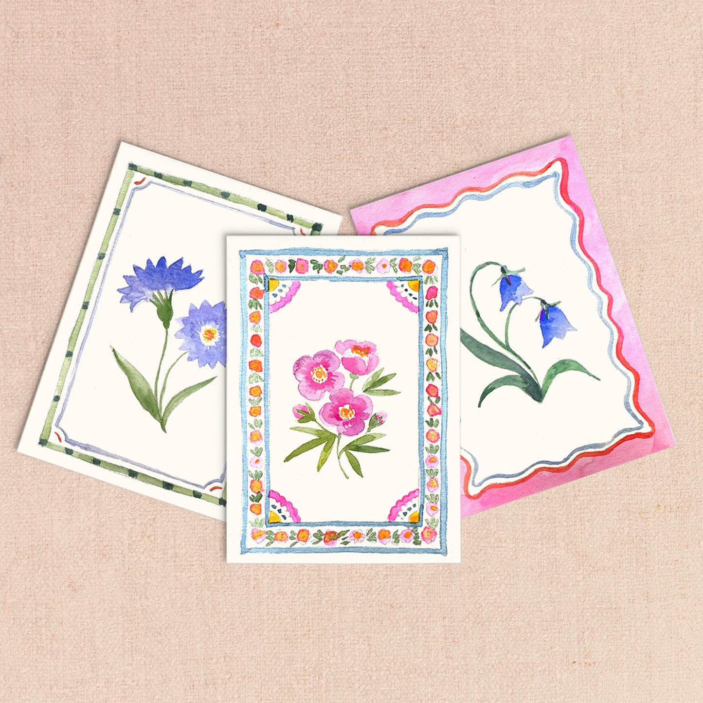 Three floral greeting cards on a beige background