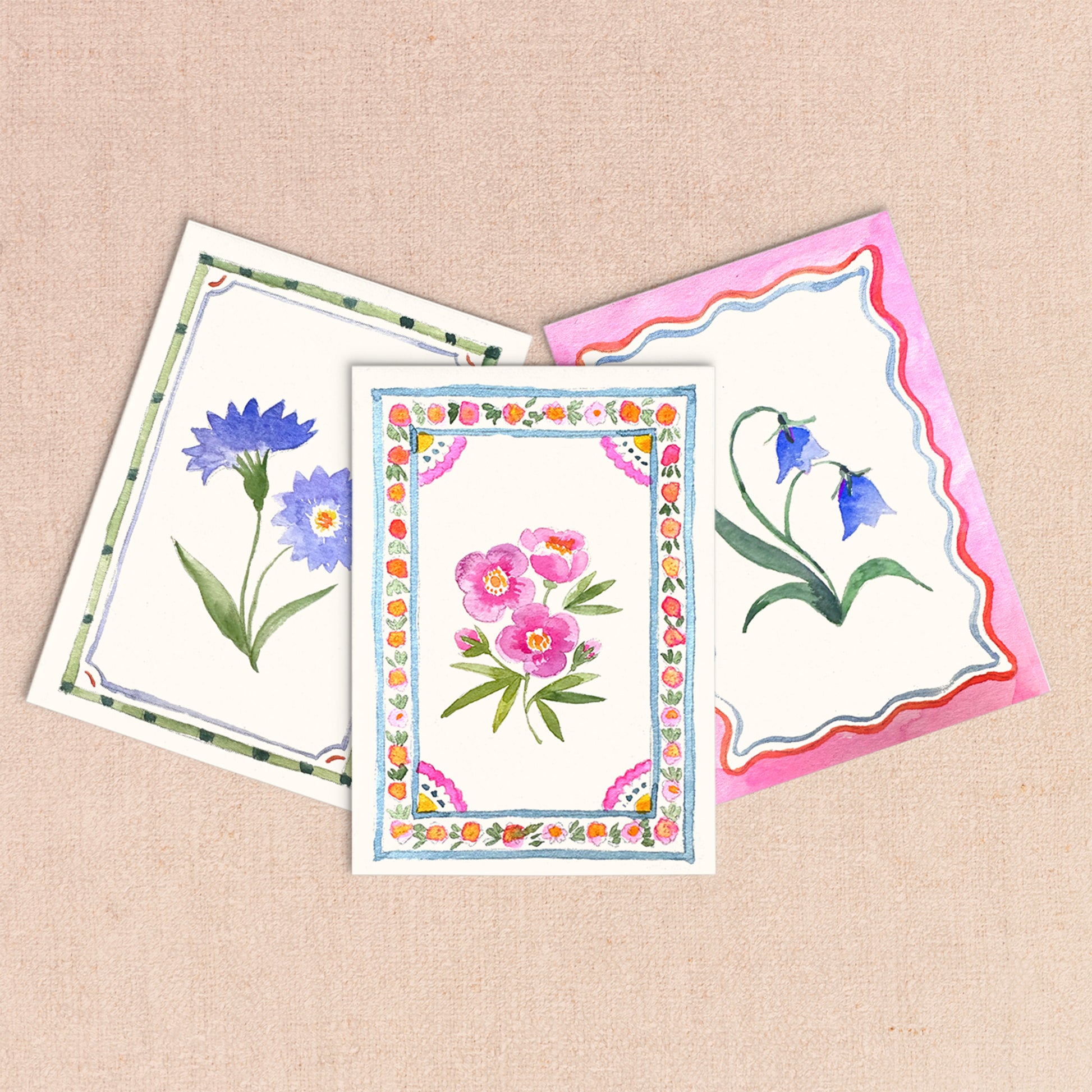 Three floral greeting cards on a beige background