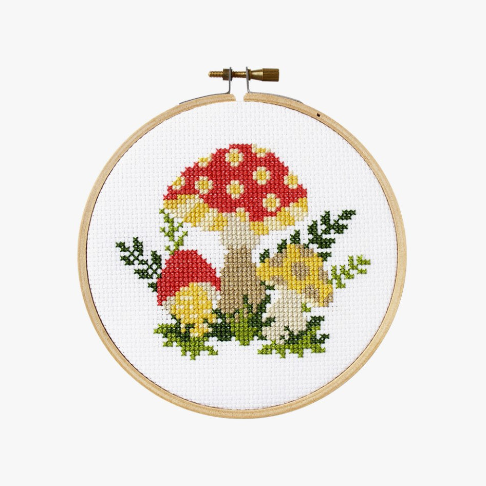 Cross stitch kit with fabric, wooden hoop, thread, needle, and instructions for beginners, featuring a mushroom design.