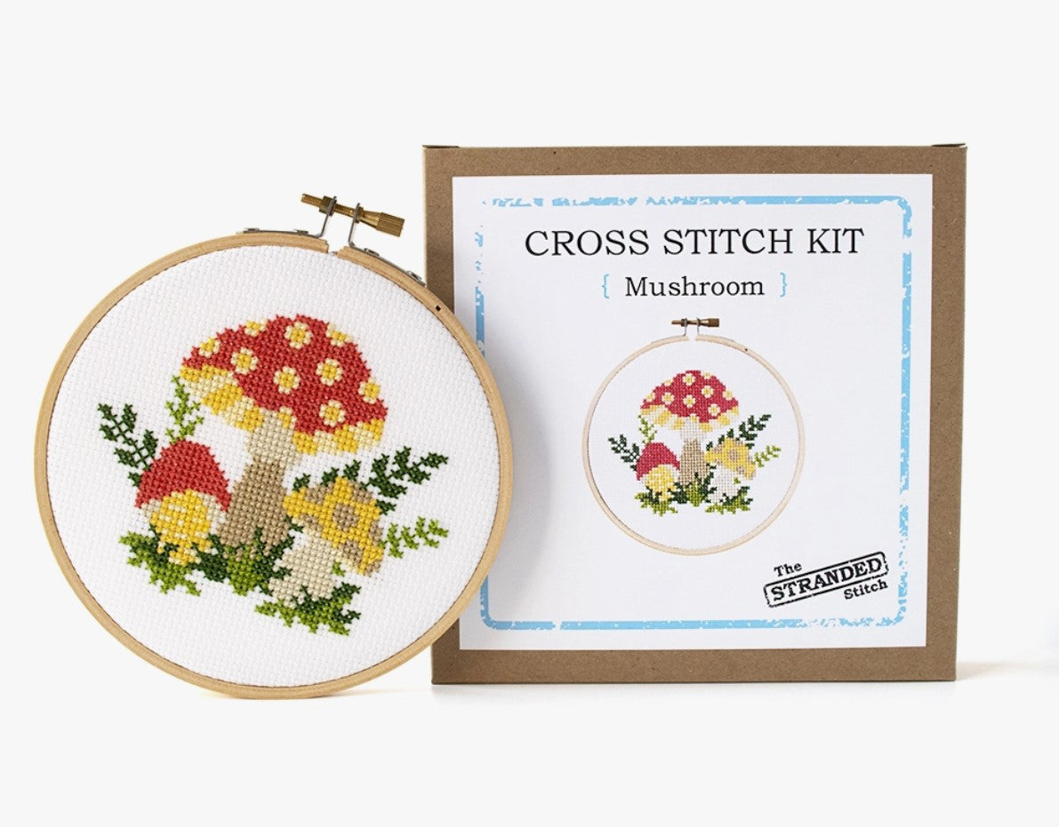 Cross stitch kit with fabric, wooden hoop, thread, needle, and instructions for beginners, featuring a mushroom design.