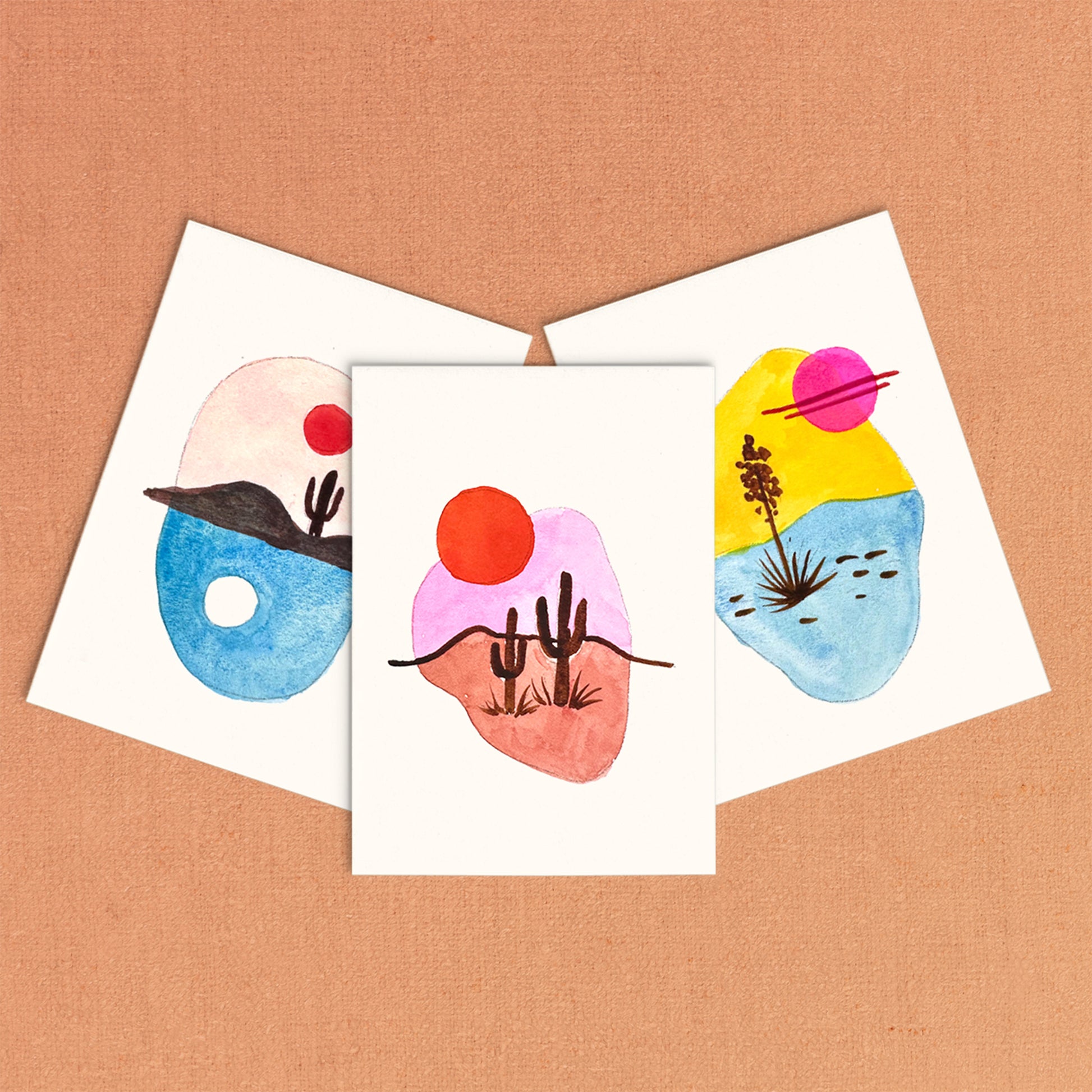 Three colorful abstract art cards on a brown background