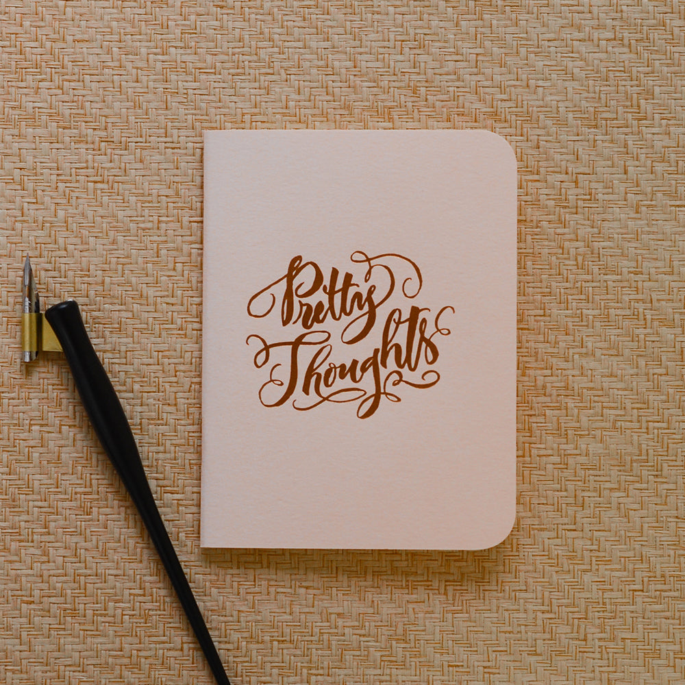 Pink softcover staple-bound notebook with "pretty thoughts" and gold accent