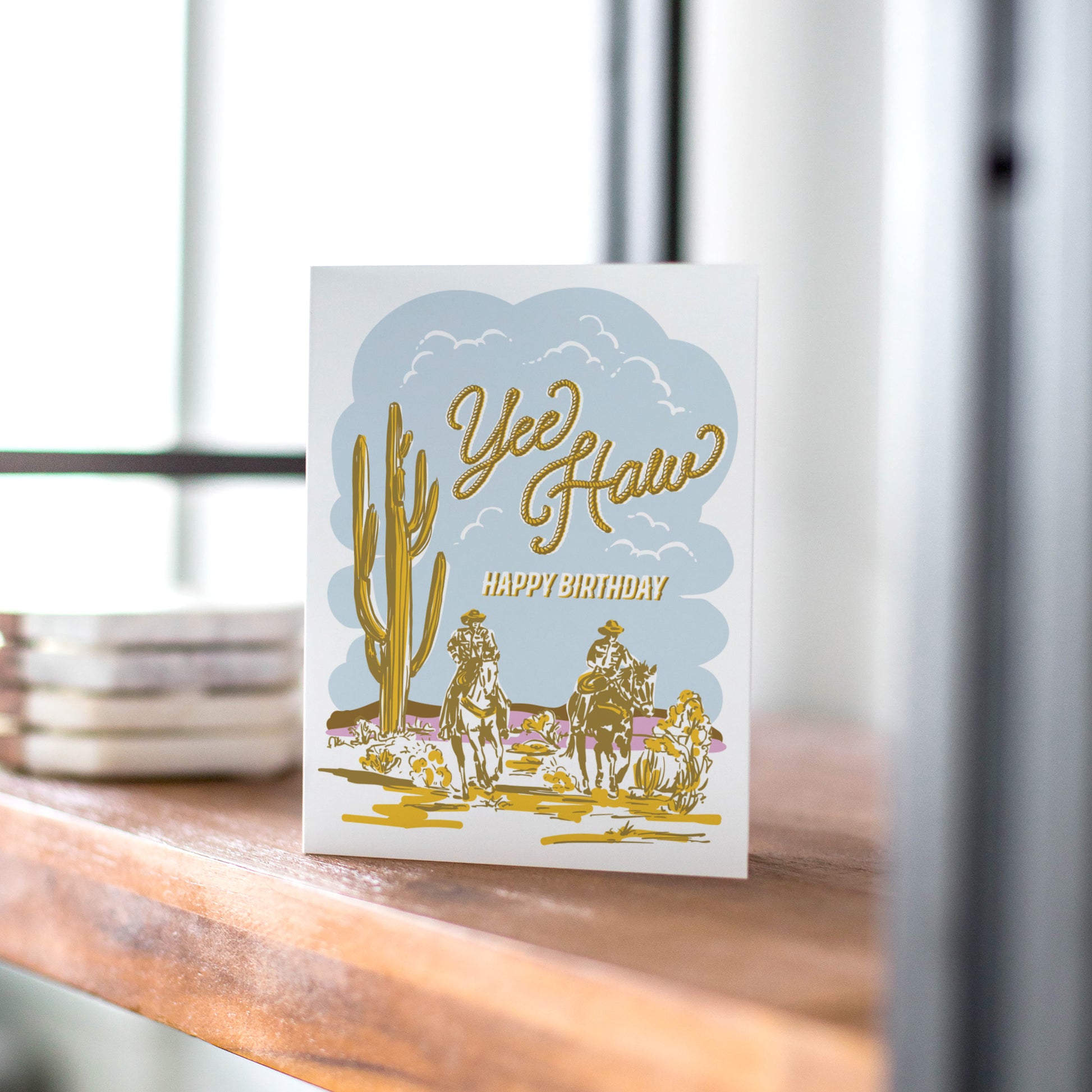 Western-themed birthday card with 'Yee Haw' text, two cowboys on horseback, cactus, and desert scene.