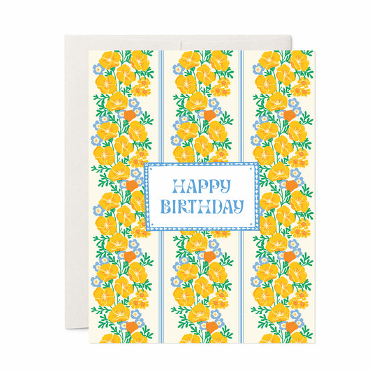Birthday card with vertical stripes of yellow poppies and blue flowers surrounding “Happy Birthday” text in a blue frame.
